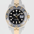 Rolex watch with black dial and gold and silver case on a white background