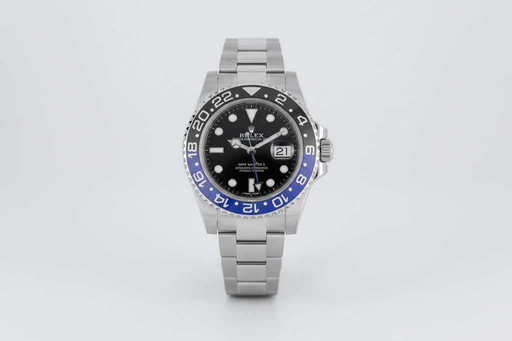 Rolex watch with black face and blue bezel on a white background
