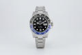 Rolex watch with black face and blue bezel on a white background