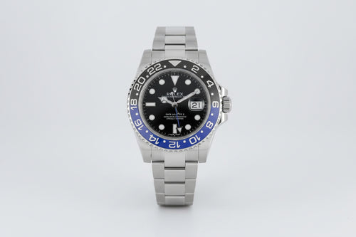 Rolex watch with black face and blue bezel on a white background